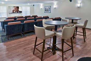 Theater room with three rows of seating facing the TV and two high top tables.